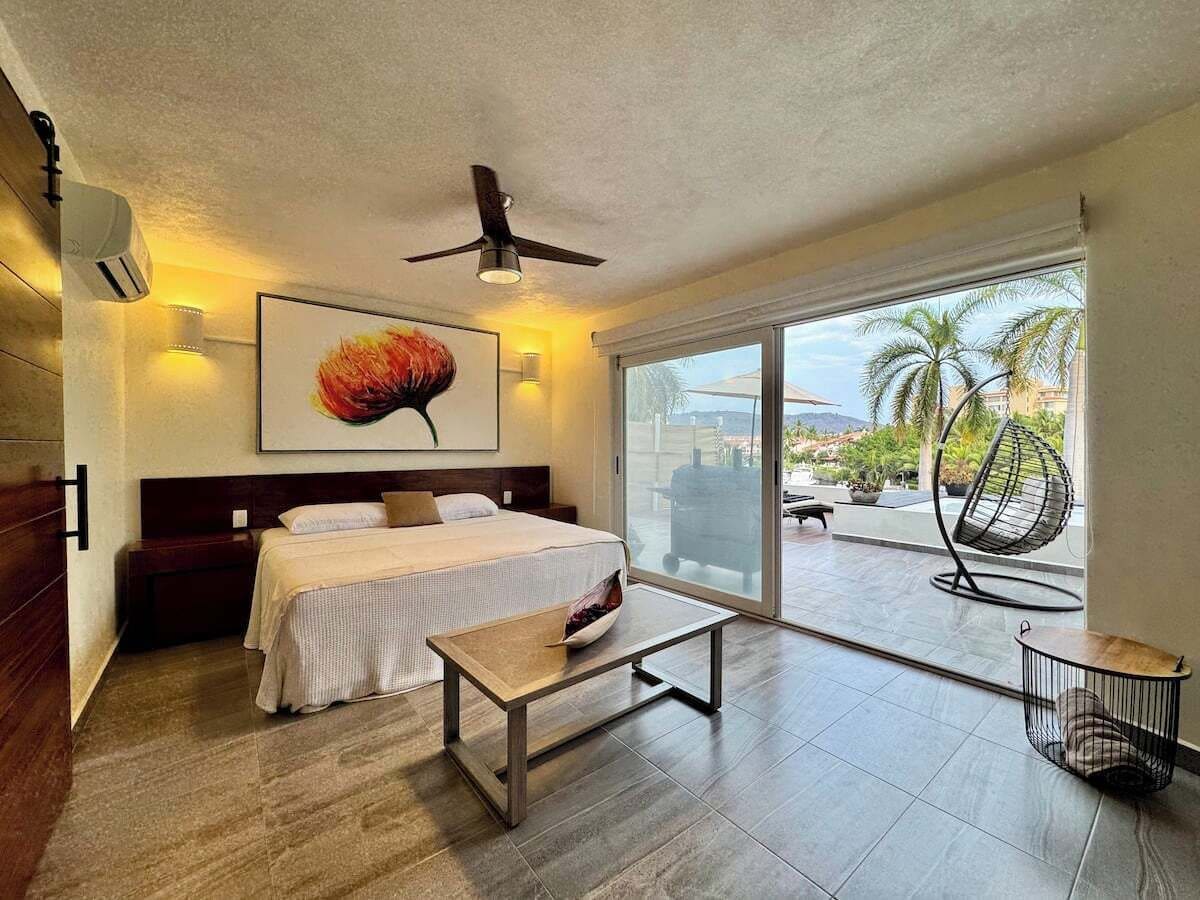 Une chambre d’hôtel avec un lit, une table, un ventilateur de plafond et une vue sur l’extérieur.