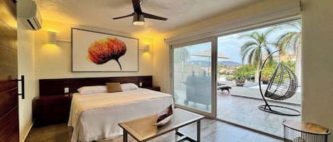 Une chambre d’hôtel avec un lit, une table, un ventilateur de plafond et une vue sur l’extérieur.