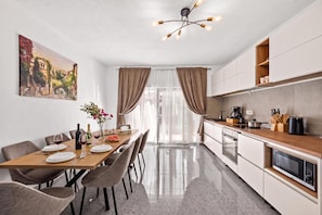 A modern kitchen with a dining area, featuring a wooden table set for a meal, a coffee machine, and a microwave. - Holiday House Lana With Pool, Biograd na Moru, Croatia (Biograd na Moru)