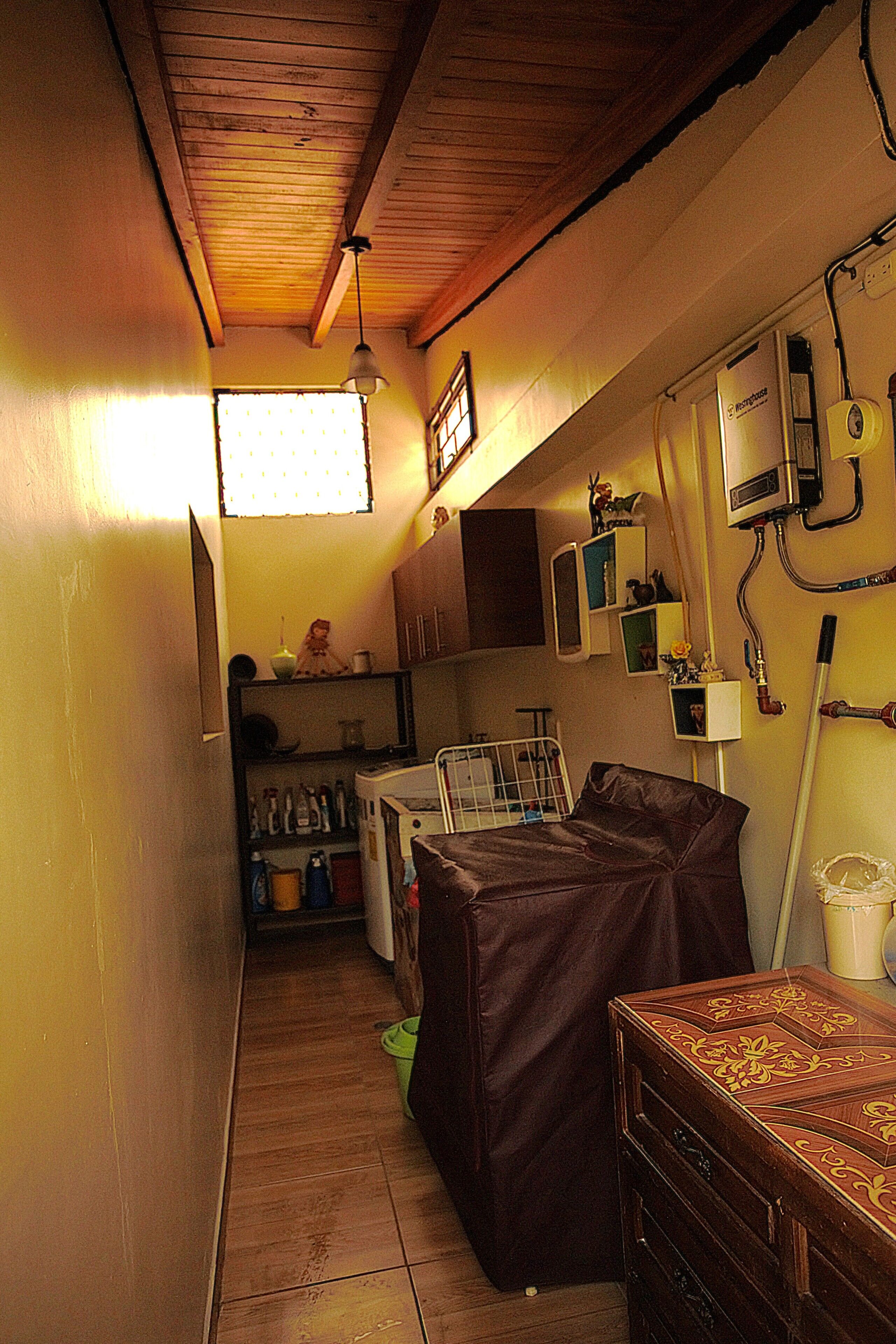 A narrow hallway with a bed, a chest of drawers, and a window with blinds.