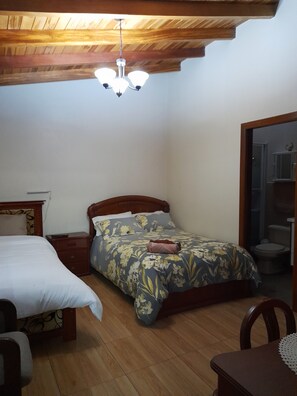 Une chambre à coucher avec un lit, une table de chevet et un luminaire au plafond.