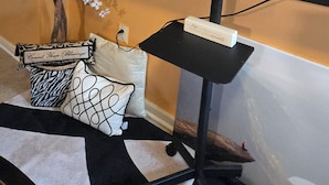 A television on a stand with a decorative tree and pillows.