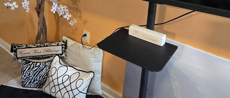 A television on a stand with a decorative tree and pillows.