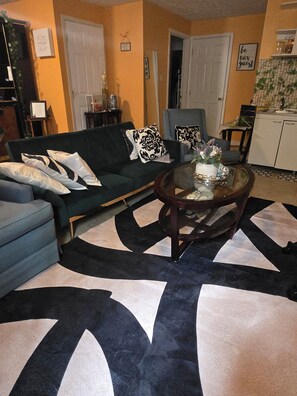 A living room with a sofa, chairs, a coffee table, and a patterned rug.