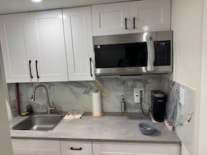 A kitchen with white cabinets, a stainless steel sink, a microwave, and a coffee maker. - Clean and Comfortable Home (Winnipeg)