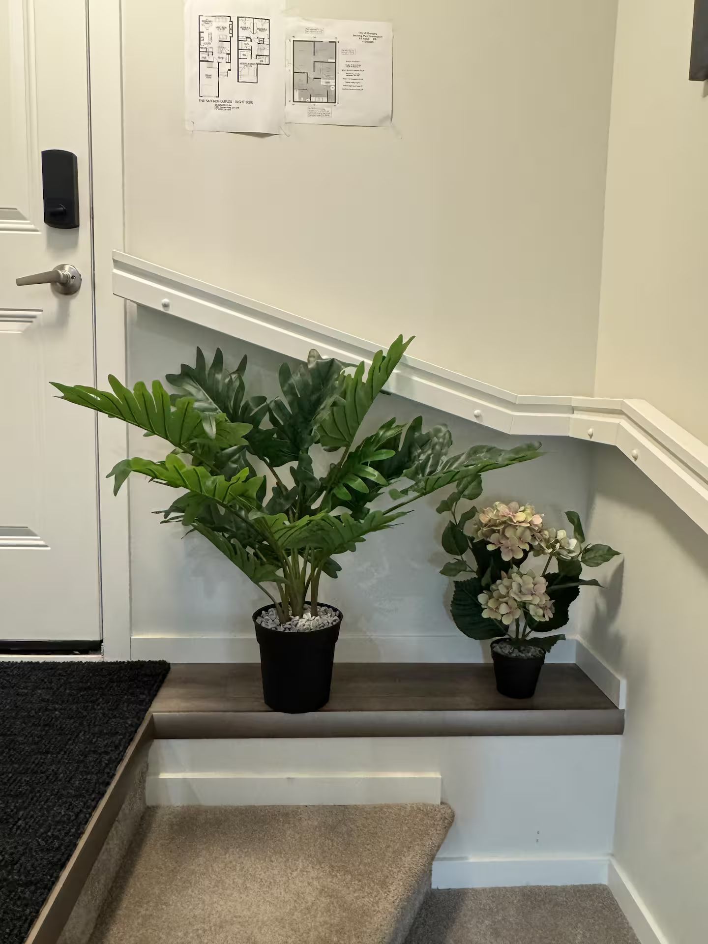A staircase with a potted plant and a small flower arrangement on the landing.