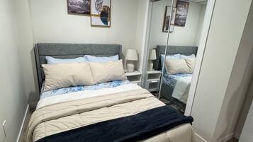 A bedroom with a bed, bedside tables, a mirror, and artwork on the wall.