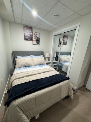 A bedroom with a bed, bedside tables, a mirror, and artwork on the wall. - Clean and Comfortable Home (Winnipeg)