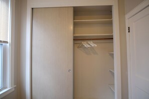 A walk-in closet with a sliding door, wooden shelves, and a hanging rod. - Chicago Life Apartment - 3 bedroom (Chicago)