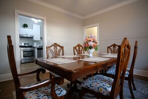 Un comedor con una mesa de madera, sillas y un jarrón de flores.