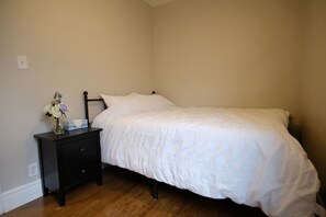 Un dormitorio con una cama individual, una mesita de noche con un florero y un enchufe.