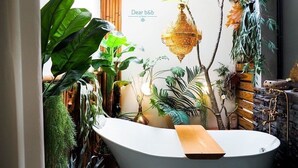 A bathroom with a freestanding bathtub, various plants, and a hanging light fixture. - FAS Glass House II - Color Space BnB (Xincheng)