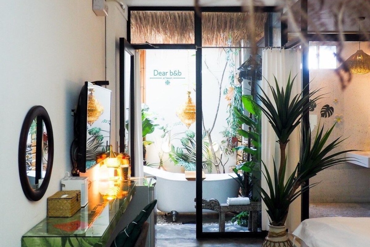 Un baño con bañera, espejo, lavamanos y una planta en maceta.