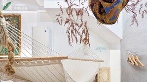 A hammock in a room with a refrigerator, a hanging plant, and a wooden chair. - FAS Glass House II - Color Space BnB (Xincheng)
