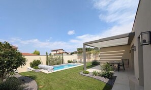 A backyard with a swimming pool, a covered patio area, and a lawn. - Vrbo Property (MILLERY)