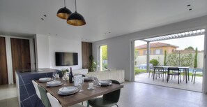 A modern kitchen with a dining area, a TV mounted on the wall, and a patio with outdoor seating. - Vrbo Property (MILLERY)
