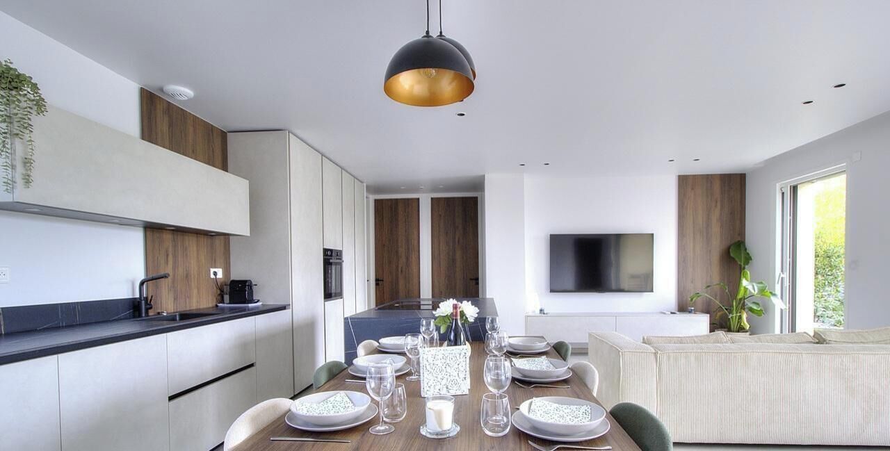 Een moderne keuken met een eethoek, een flatscreen televisie en een groot raam.