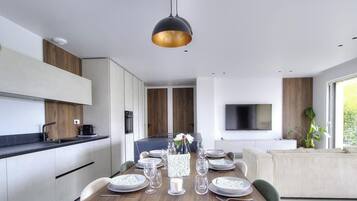 Een moderne keuken met een eethoek, een flatscreen televisie en een groot raam.