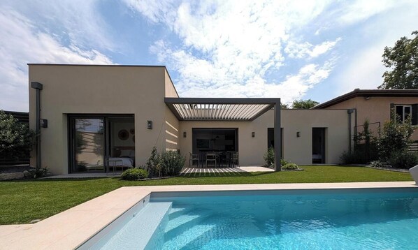 A modern house with a swimming pool, a patio, and a covered outdoor seating area. - Vrbo Property (MILLERY)