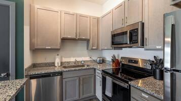 A modern kitchen with stainless steel appliances, granite countertops, and wooden cabinets.