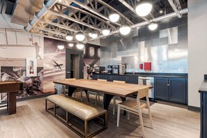 A modern kitchen with a wooden dining table, bench seating, and stainless steel appliances.