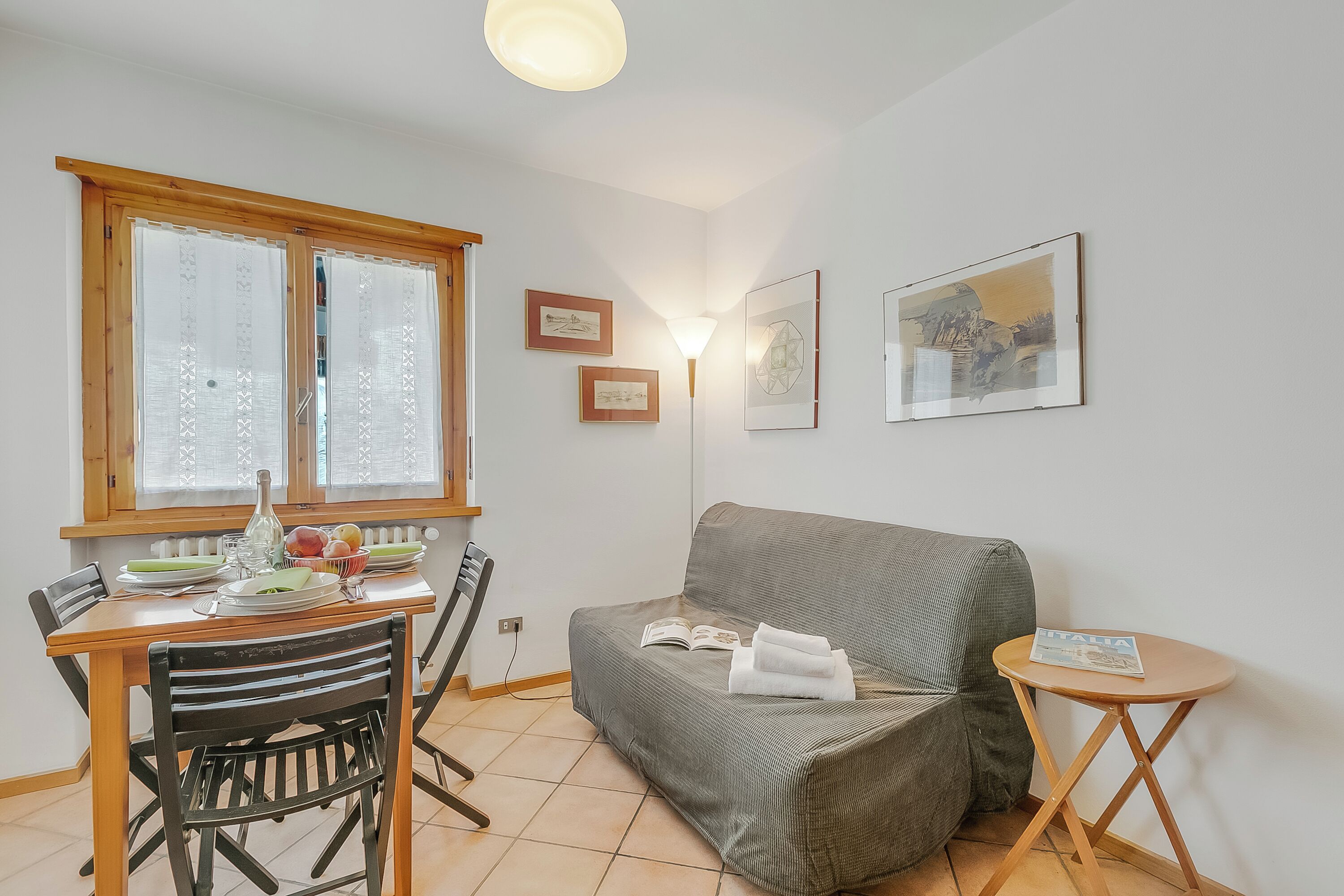 A cozy living area with a dining table, chairs, a sofa, and a small side table with a magazine.