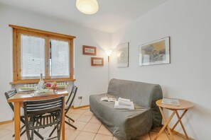 Zona d'estar acollidora amb taula de menjador, cadires, sofà i taula auxiliar petita amb una revista.