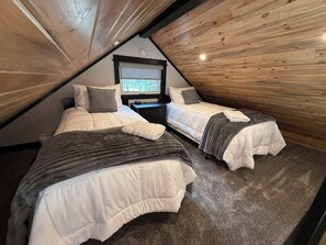 A bedroom with two beds, a nightstand, and a window.