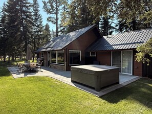 A modern house with a patio, outdoor furniture, and a large window.