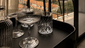 Varanda com mesa e cadeiras, vista para paisagem urbana com montanhas.