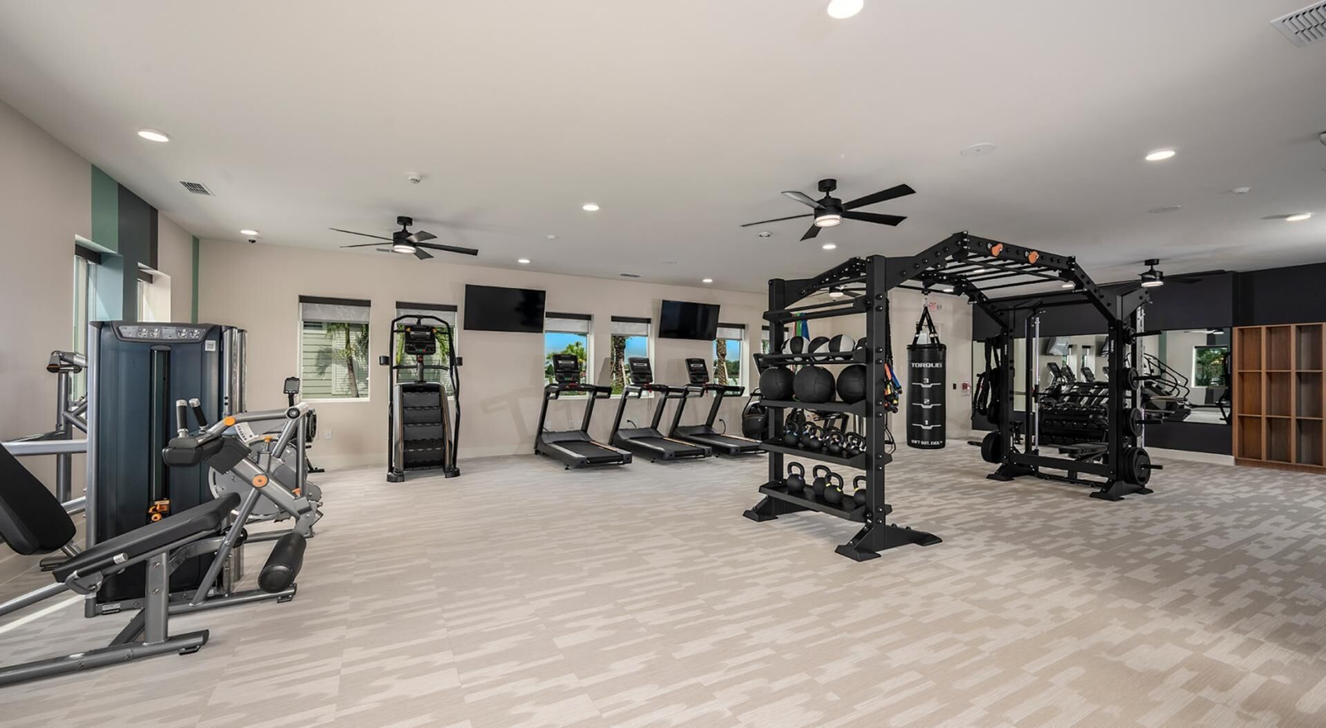 Une salle de sport équipée de tapis de course, d’appareils de musculation et d’un support pour les exercices de squat.