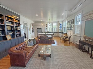 A spacious living room with a leather sofa, a coffee table, and a dining area with chairs.