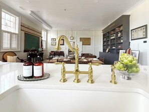 A well-lit room with a white sink, brass fixtures, a globe, and a bookshelf.