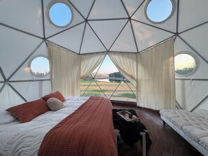 A yurt with a bed, a small table, and a view of a lake. - Unique Geodesic Dome overlooking the iconic Missouri River (Great Falls)