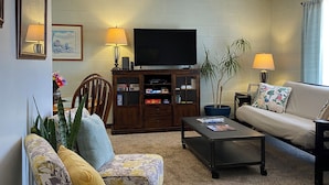 Ein Wohnzimmer mit Sofa, Couchtisch, Fernseher und Schrank.