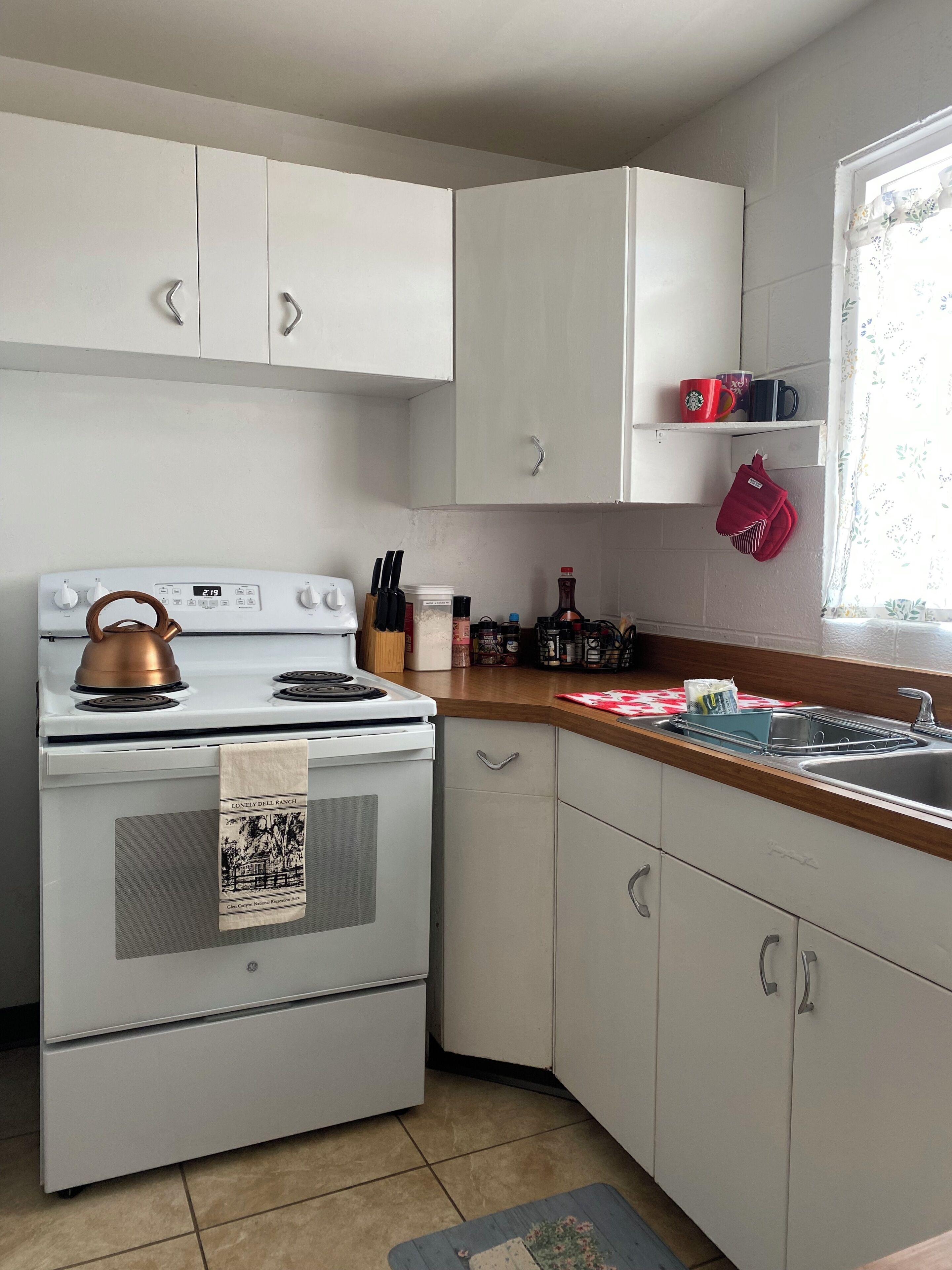 A kitchen with white cabinets, a stove, and a sink.
