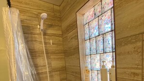 Ein Badezimmer mit Dusche, Badewanne und einem Buntglasfenster.