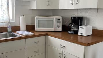 A kitchen with white cabinets, a microwave, a coffee maker, and a toaster.