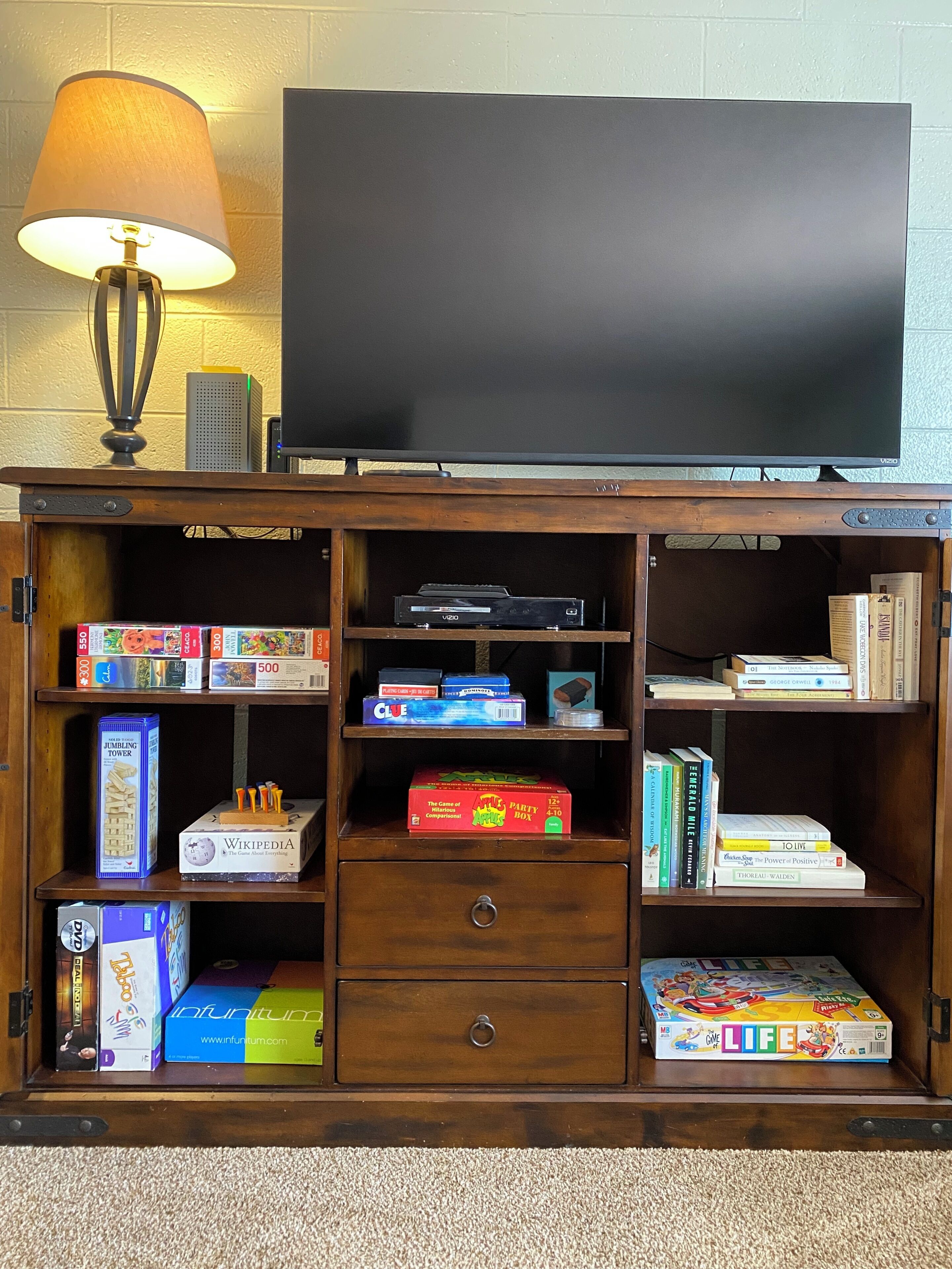 Een houten tv-meubel met een televisie, boeken en gezelschapsspellen.