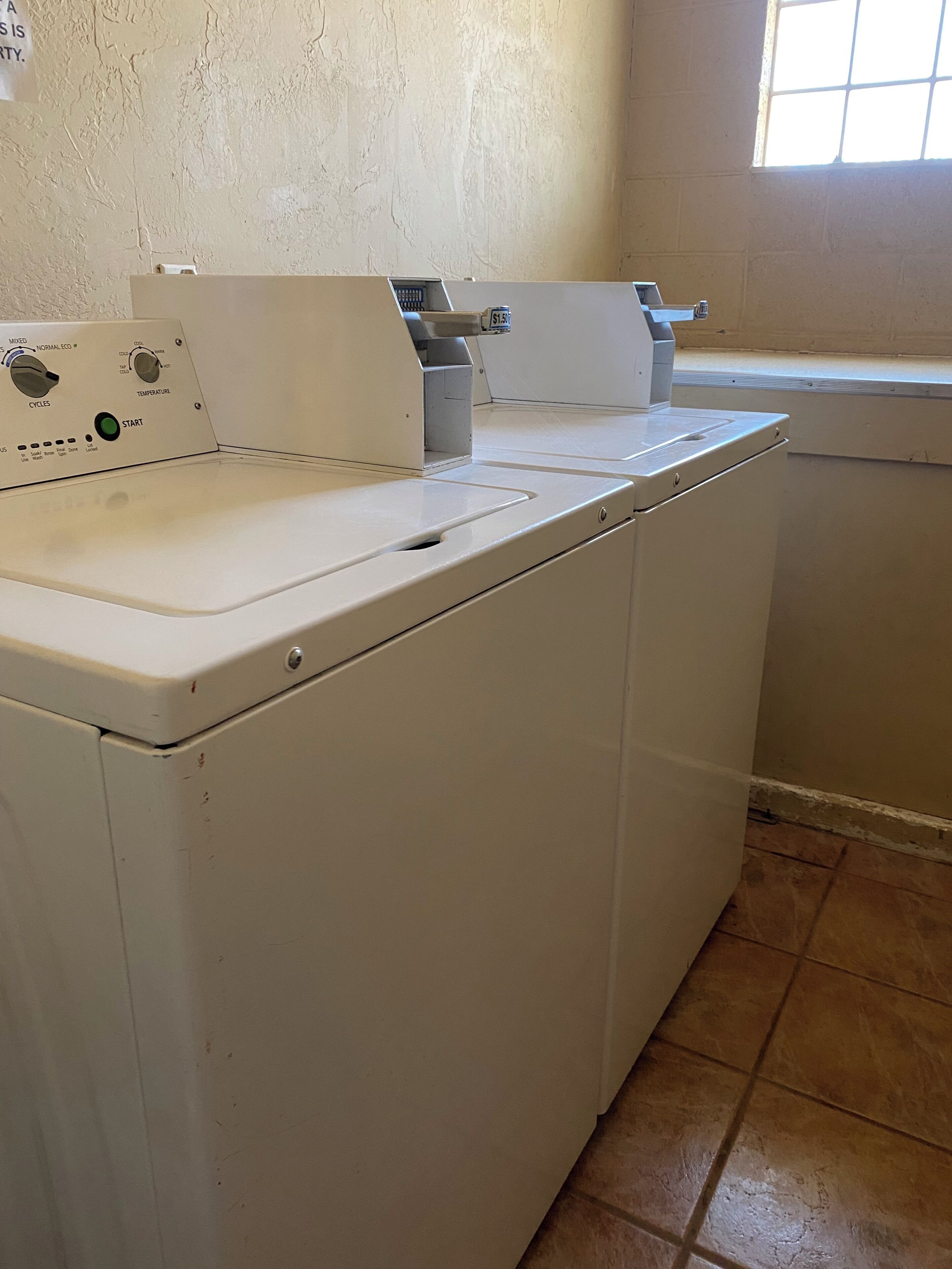 A front-loading washing machine with a control panel, a dryer, and a window above the dryer.