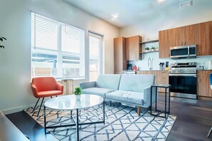 A modern apartment with a living area, kitchen, and large windows. - Boulevard Stays Stylish 1BR Getaway Pool, Gym & Free Parking (Dallas)