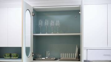 Eine Küche mit einem weißen Schrank, einem Weinregal und einer Tablett mit Gläsern.