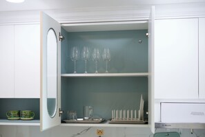 Eine Küche mit einem weißen Schrank, einem Weinregal und einer Tablett mit Gläsern.