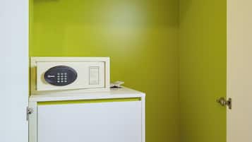 A bathroom with a green wall, a white cabinet with drawers, and a digital shower control panel.