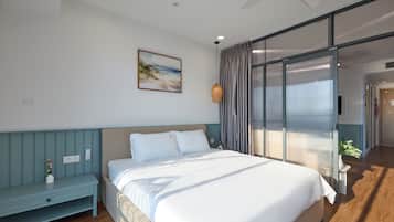 A bedroom with a bed, a nightstand, a painting, and a view through a sliding door.