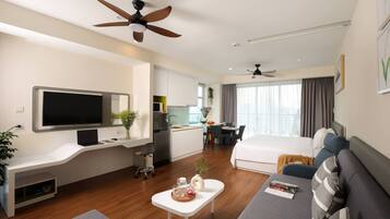 Ein modernes Hotelzimmer mit Fernseher, Schreibtisch mit Laptop, Essbereich und Bett.