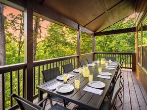 An outdoor dining area with tables and chairs, surrounded by a wooden deck and trees. - Indoor Pool • Hot Tub • Theater • Games • Views (Sevierville)