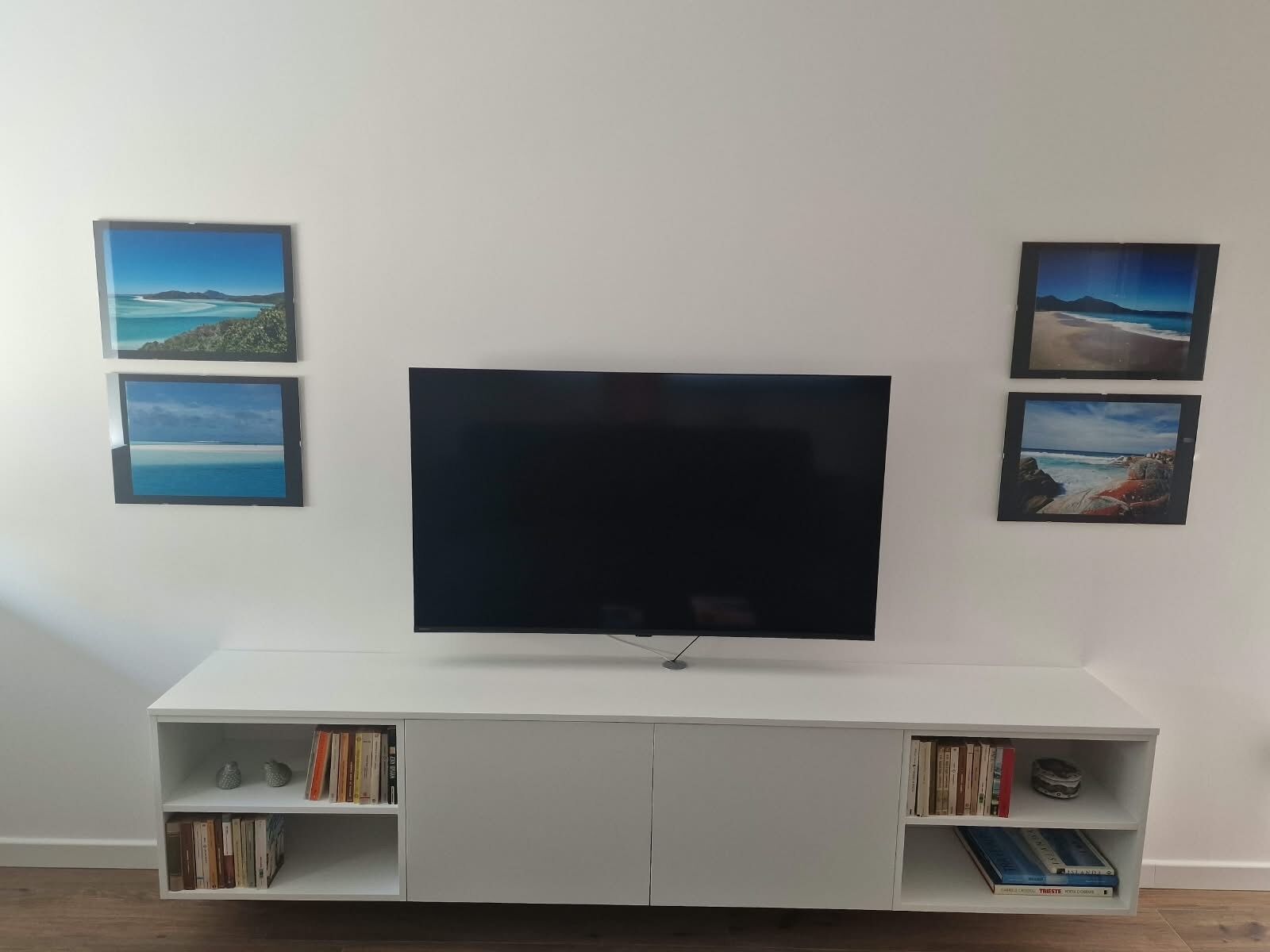 Ein Flachbildfernseher an einer weißen Unterhaltungseinheit, darunter Bücherregale.