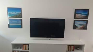 Ein Flachbildfernseher an einer weißen Unterhaltungseinheit, darunter Bücherregale.
