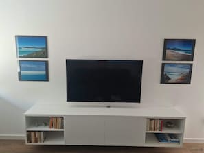 Ein Flachbildfernseher an einer weißen Unterhaltungseinheit, darunter Bücherregale.